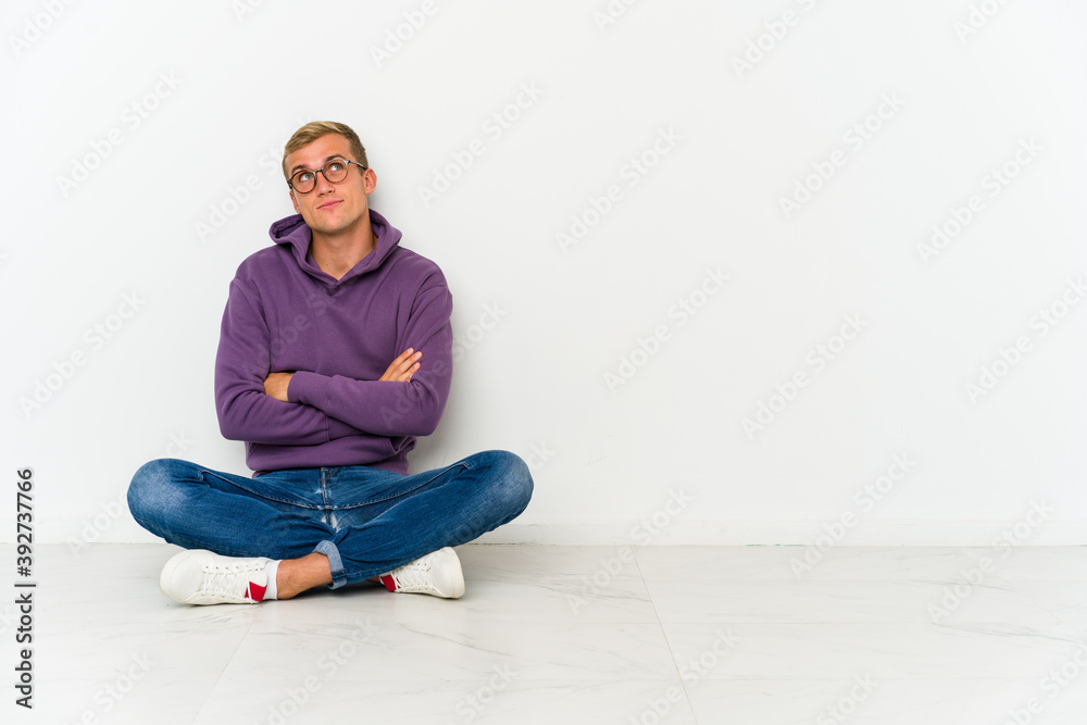 Young caucasian man sitting on the floor dreaming of achieving goals and purposes Young caucasian man sitting on the floor dreaming of achieving goals and purposes