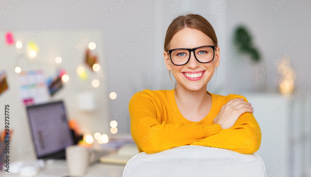 happy smiling freelancer woman in a yellow sweater resting at  workplace with Christmas lights.