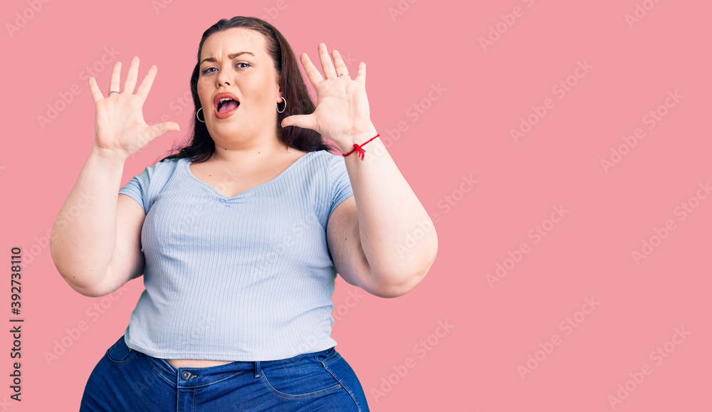 Young plus size woman wearing casual clothes afraid and terrified with fear expression stop gesture with hands, shouting in shock. panic concept.