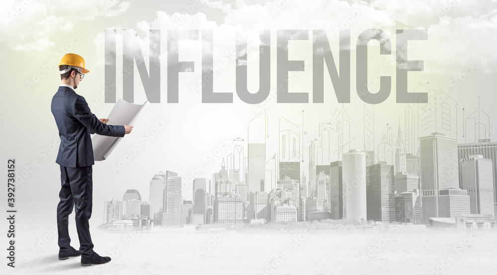 Young businessman with hard hat and INFLUENCE inscription, new business opportunity concept Young businessman with hard hat and INFLUENCE inscription, new business opportunity concept