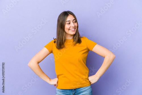 Young caucasian woman laughs happily and has fun keeping hands on stomach.