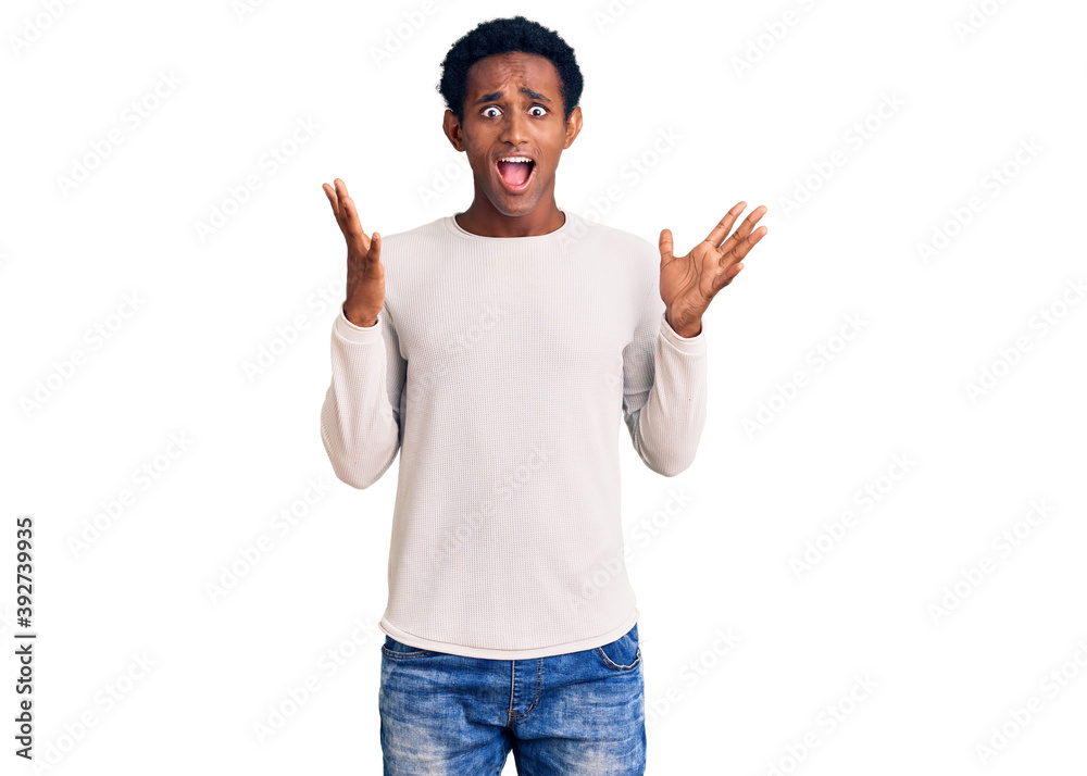 African handsome man wearing casual winter sweater celebrating crazy and amazed for success with arms raised and open eyes screaming excited. winner concept African handsome man wearing casual winter sweater celebrating crazy and amazed for success with arms raised and open eyes screaming excited. winner concept