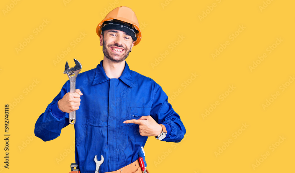 Young hispanic man wearing electrician uniform holding wrench pointing finger to one self smiling happy and proud Young hispanic man wearing electrician uniform holding wrench pointing finger to one self smiling happy and proud