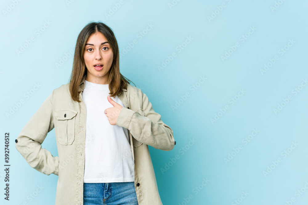 Young caucasian woman surprised pointing with finger, smiling broadly.