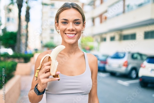 Young cauciasian fitness woman wearing sport clothes training outdoors eating healthy banana for strength and energy photo