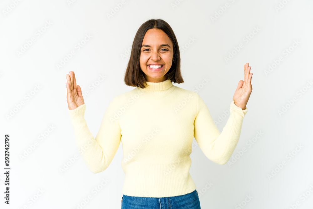 Young mixed race woman holding something little with forefingers, smiling and confident.