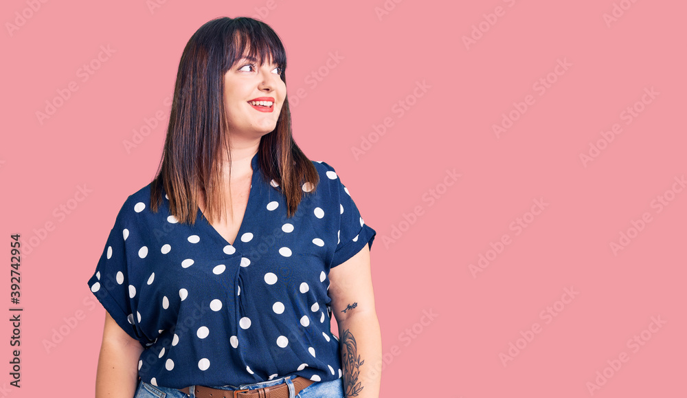 Young plus size woman wearing casual clothes looking away to side with smile on face, natural expression. laughing confident. Young plus size woman wearing casual clothes looking away to side with smile on face, natural expression. laughing confident.