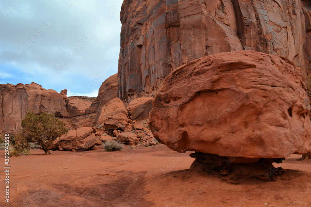A giant red stone under a high rock in the Monument Valley, Utah