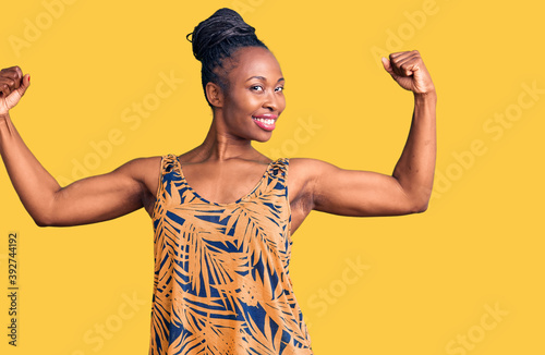 Young african american woman wearing casual clothes showing arms muscles smiling proud. fitness concept.