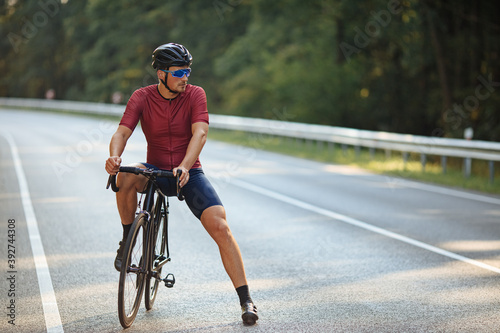 Male athlete relaxing on bicycle among nature