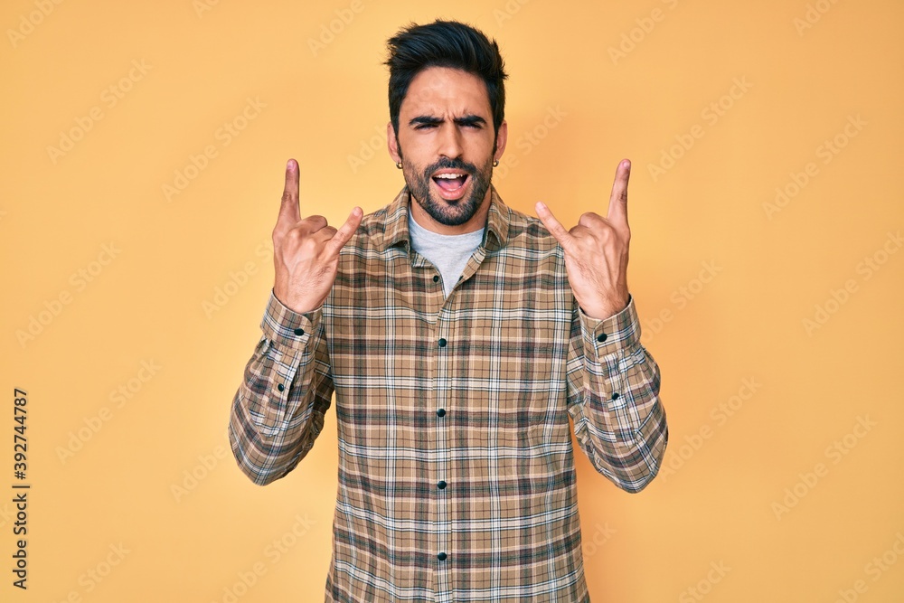 Fototapeta premium Handsome hispanic man with beard wearing casual clothes shouting with crazy expression doing rock symbol with hands up. music star. heavy concept.