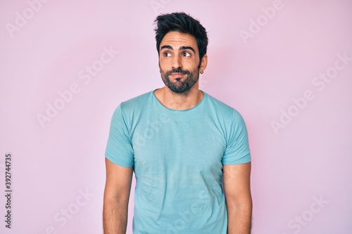 Handsome hispanic man with beard wearing casual clothes smiling looking to the side and staring away thinking.