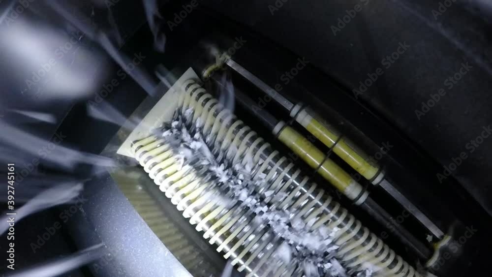 Underside of paper shredder with shredded paper falling into hopper Underside of paper shredder with shredded paper falling into hopper