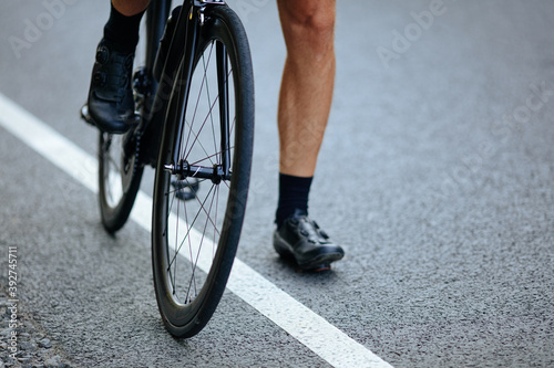 Close up of male muscular legs sitting on bike outdoors