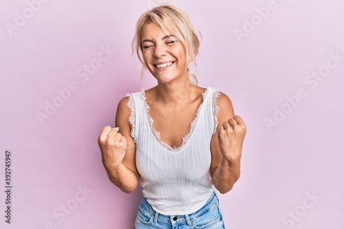 Young blonde girl wearing casual clothes very happy and excited doing winner gesture with arms raised  smiling and screaming for success. celebration concept.