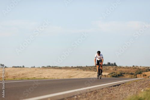 Strong cyclist having long distance racing on asphalt road