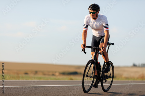 Muscular guy in sportswear riding bike on road