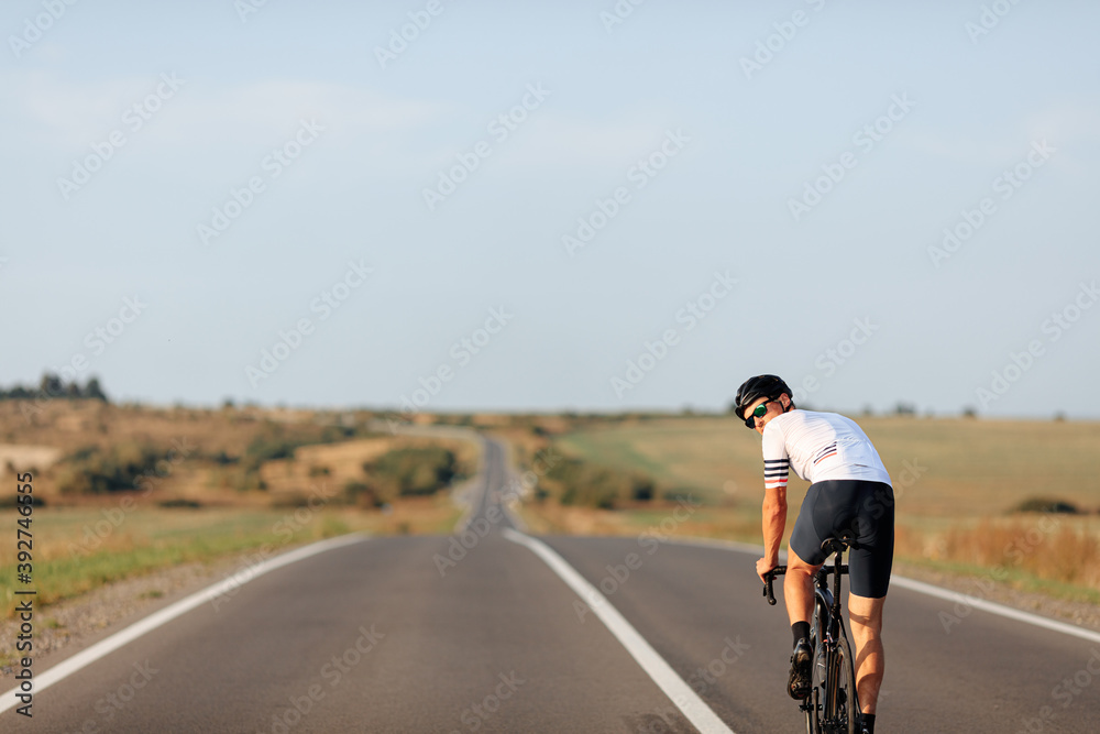 Man in eyewear and helmet cycling in the middle of road Man in eyewear and helmet cycling in the middle of road