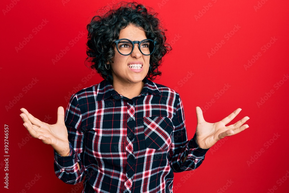 Hispanic woman with curly hair wearing casual clothes and glasses showing and pointing up with fingers number three while smiling confident and happy. Hispanic woman with curly hair wearing casual clothes and glasses showing and pointing up with fingers number three while smiling confident and happy.