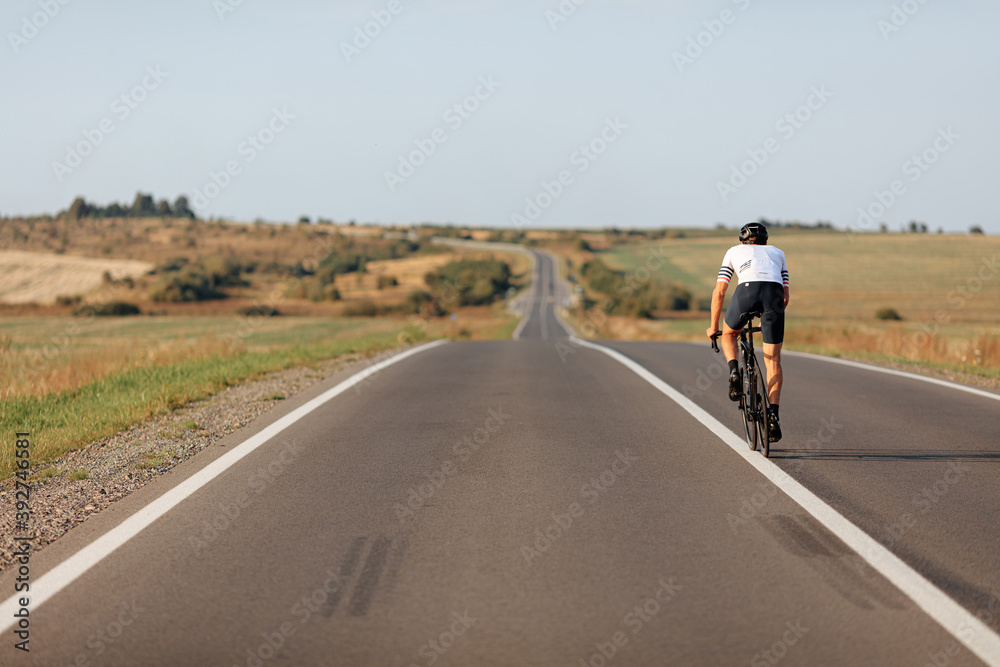 Obraz premium Sporty man cycling on white separation line of road