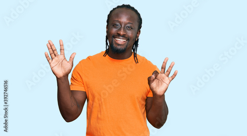Handsome young african american man wearing casual clothes showing and pointing up with fingers number eight while smiling confident and happy.