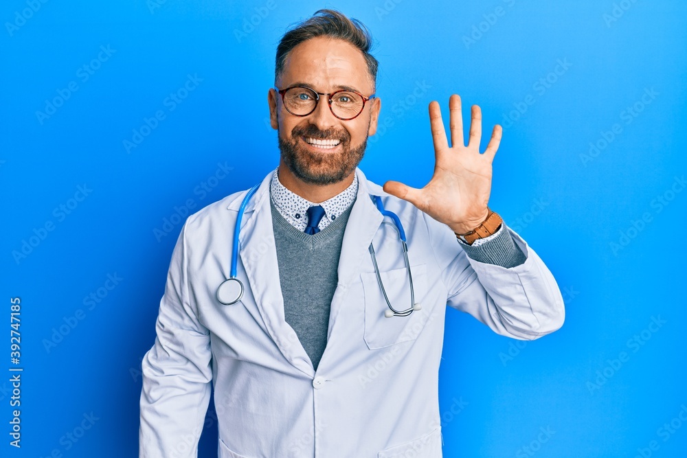 Handsome middle age man wearing doctor uniform and stethoscope showing and pointing up with fingers number five while smiling confident and happy.
