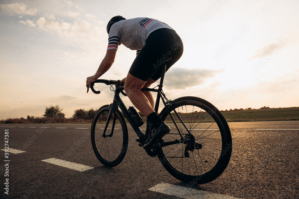 Muscular man in helmet riding bike in half bent position Muscular man in helmet riding bike in half bent position
