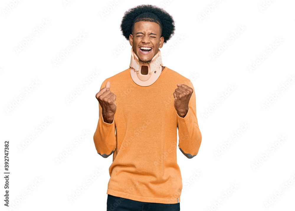 African american man with afro hair wearing cervical neck collar excited for success with arms raised and eyes closed celebrating victory smiling. winner concept. African american man with afro hair wearing cervical neck collar excited for success with arms raised and eyes closed celebrating victory smiling. winner concept.
