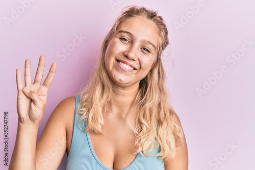 Young blonde girl wearing casual clothes showing and pointing up with fingers number four while smiling confident and happy.