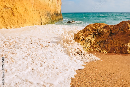 Waves crash on rocks on the sandy shores of benagil beach in portugal