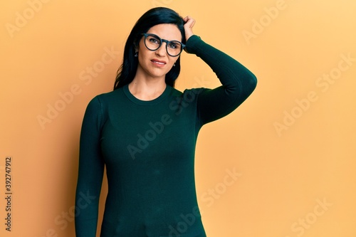 Young caucasian woman wearing casual clothes and glasses confuse and wonder about question. uncertain with doubt, thinking with hand on head. pensive concept.