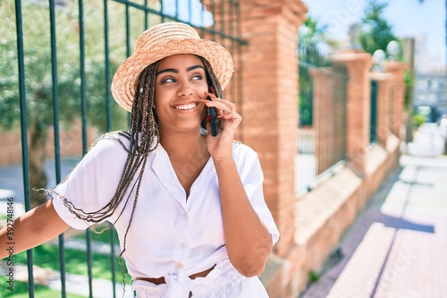 Young african american woman with braids smiling happy talking on smartphone outdoors on a sunny day of summer