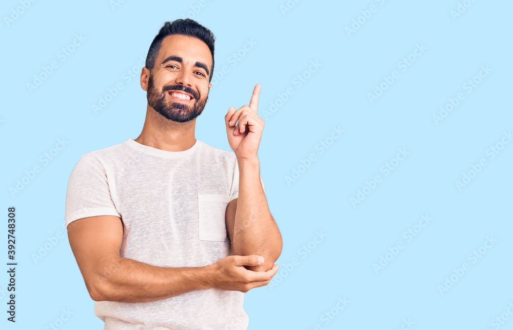 Young hispanic man wearing casual clothes with a big smile on face, pointing with hand and finger to the side looking at the camera. Young hispanic man wearing casual clothes with a big smile on face, pointing with hand and finger to the side looking at the camera.