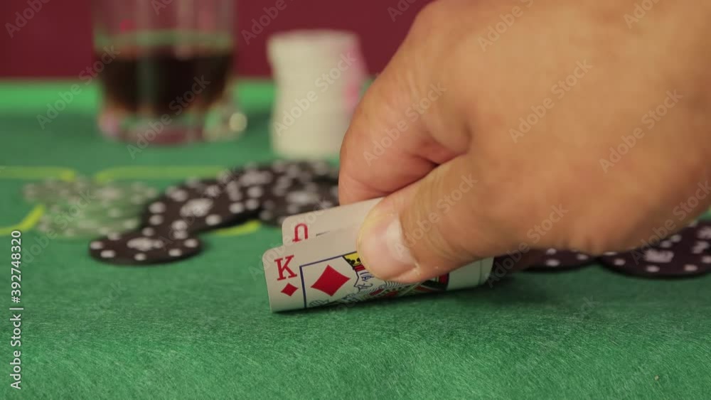 Close-up hand in a casino at a gambling table raises cards. The winning combination of queen and king of diamonds fell out. In the background, in the out-of-focus, there is a highball glass. UHD. Close-up hand in a casino at a gambling table raises cards. The winning combination of queen and king of diamonds fell out. In the background, in the out-of-focus, there is a highball glass. UHD.