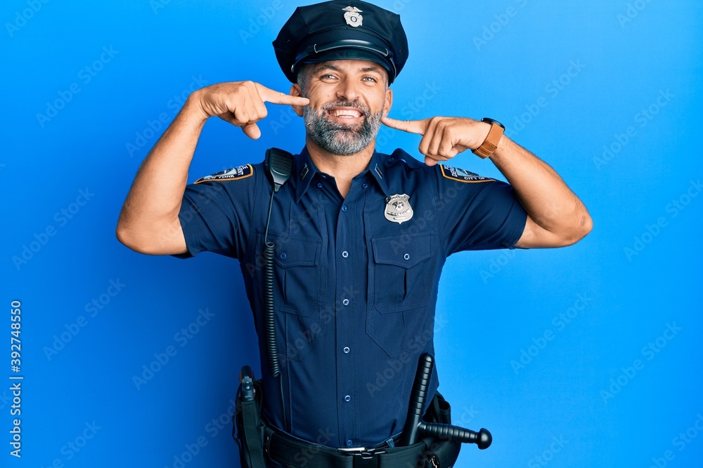 Middle age handsome man wearing police uniform smiling cheerful showing and pointing with fingers teeth and mouth. dental health concept. Middle age handsome man wearing police uniform smiling cheerful showing and pointing with fingers teeth and mouth. dental health concept.