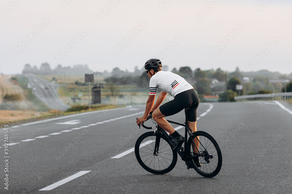 Obraz premium Young cyclist racing on road during summer day
