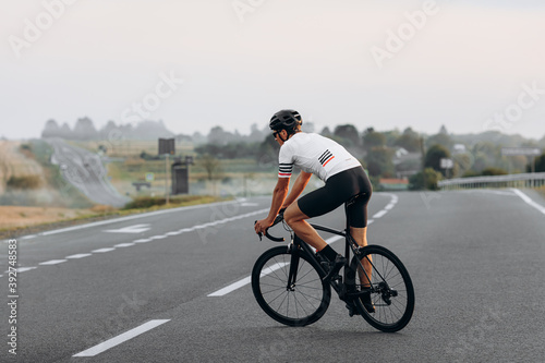 Young cyclist racing on road during summer day