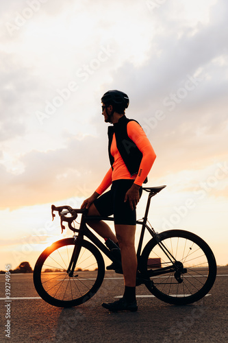 Fototapeta Naklejka Na Ścianę i Meble -  Athletic man sitting on bike and enjoying sunset