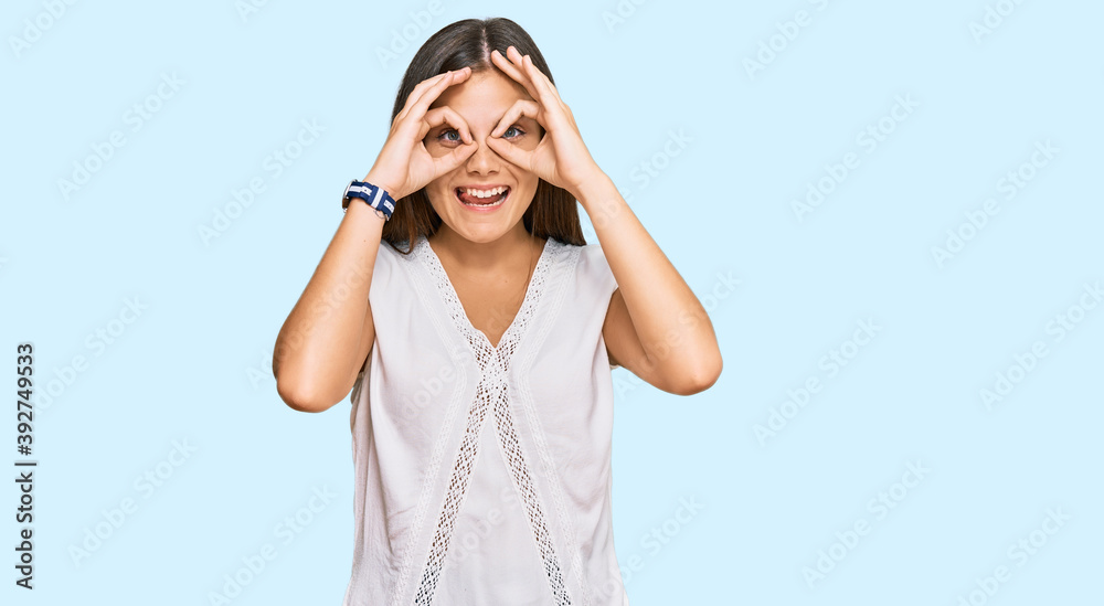 Young caucasian woman wearing casual clothes doing ok gesture like binoculars sticking tongue out, eyes looking through fingers. crazy expression. Young caucasian woman wearing casual clothes doing ok gesture like binoculars sticking tongue out, eyes looking through fingers. crazy expression.