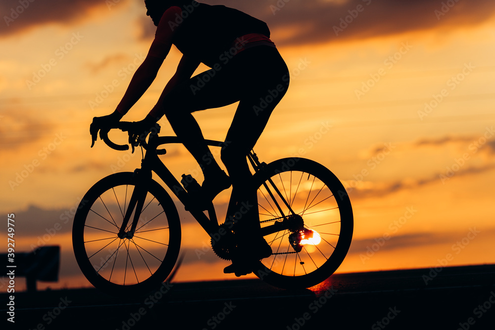 Fototapeta premium Silhouette of active man racing on road during sunset