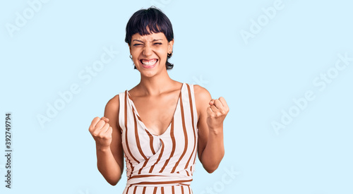 Canvastavla Young brunette woman with short hair wearing summer outfit excited for success with arms raised and eyes closed celebrating victory smiling