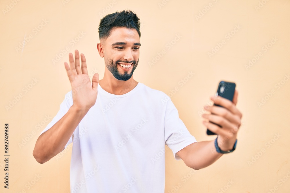 Young arab man smiling happy doing video call using smartphone at the city. Young arab man smiling happy doing video call using smartphone at the city.