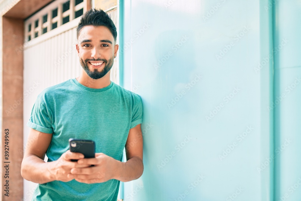 Young arab man smiling happy using smartphone at the city. Young arab man smiling happy using smartphone at the city.