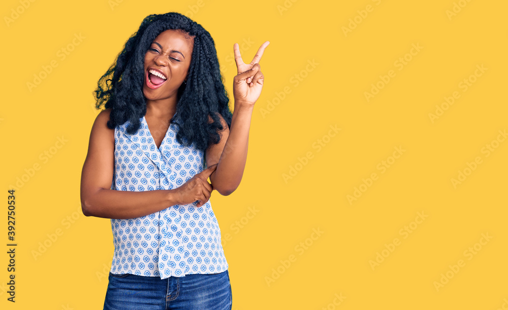 Beautiful african american woman wearing casual summer shirt smiling with happy face winking at the camera doing victory sign. number two. Beautiful african american woman wearing casual summer shirt smiling with happy face winking at the camera doing victory sign. number two.