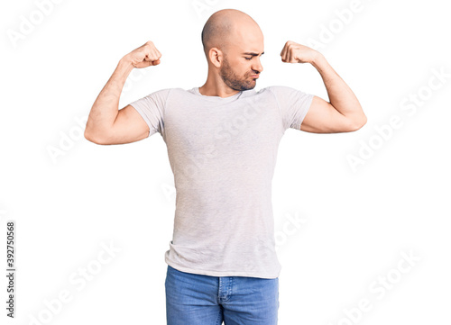 Young handsome man wearing casual t shirt showing arms muscles smiling proud. fitness concept.