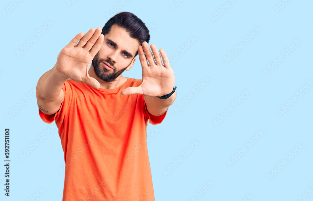 Fototapeta premium Young handsome man with beard wearing casual t-shirt doing frame using hands palms and fingers, camera perspective