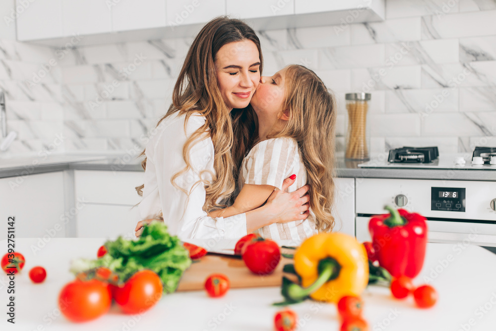 Mother with her daughter having fun and cooking salad in kitchen at home. Happy family. Mother with her daughter having fun and cooking salad in kitchen at home. Happy family.