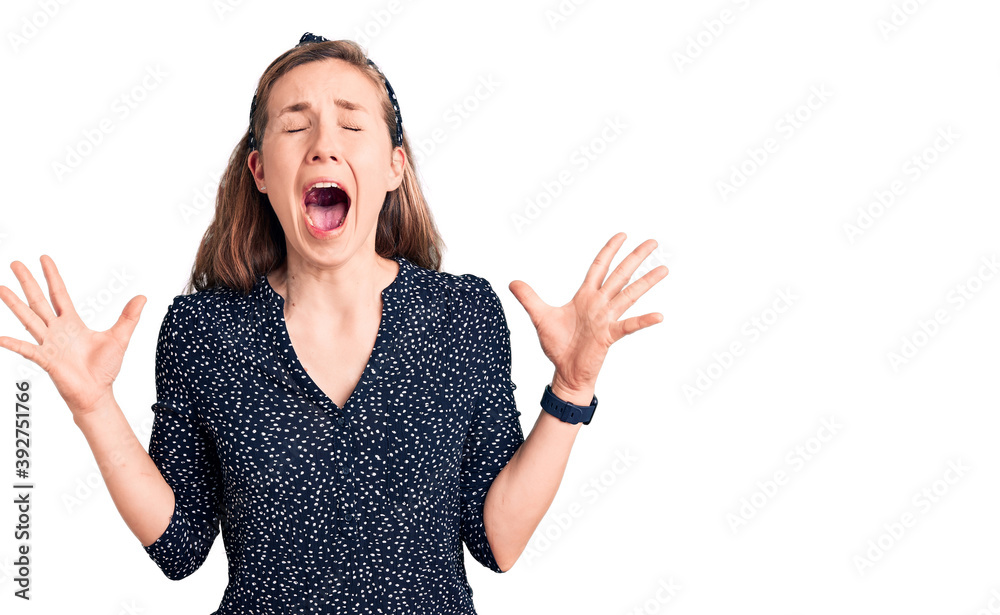 Young beautiful blonde woman wearing casual shirt celebrating mad and crazy for success with arms raised and closed eyes screaming excited. winner concept