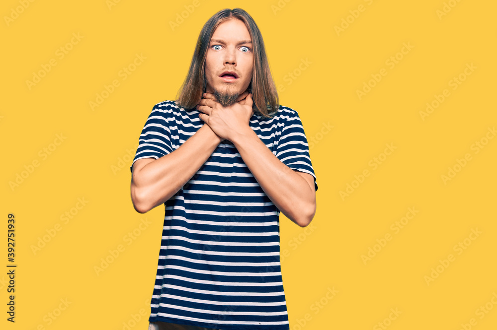 Handsome caucasian man with long hair wearing casual striped t-shirt shouting and suffocate because painful strangle. health problem. asphyxiate and suicide concept. Handsome caucasian man with long hair wearing casual striped t-shirt shouting and suffocate because painful strangle. health problem. asphyxiate and suicide concept.