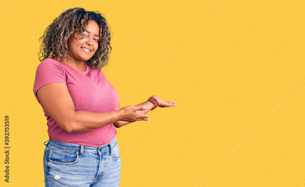 Young african american plus size woman wearing casual clothes inviting to enter smiling natural with open hand Young african american plus size woman wearing casual clothes inviting to enter smiling natural with open hand